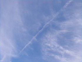 見上げると、線路跡上空に飛行機雲がひとすじ